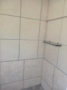 a shower with a white tiled wall and a shelf at Seabreeze Modern Apartment sleeps up to 4 people in Durban