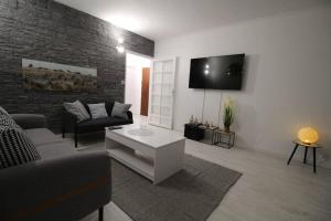 sala de estar con sofá y TV en la pared en Bel appartement meublé 4 pièces, en Ris-Orangis