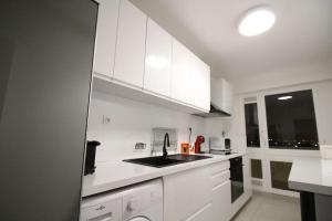 una cocina blanca con armarios blancos y fregadero en Bel appartement meublé 4 pièces, en Ris-Orangis