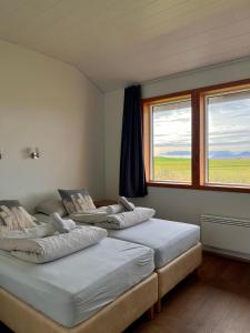 three beds in a room with two windows at Guesthouse Nypugardar in Höfn