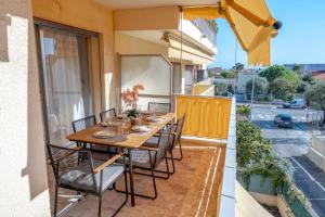 a table and chairs on a balcony with a view of a street at 3 pièces au cœur du cros de cagnes in Cagnes-sur-Mer
