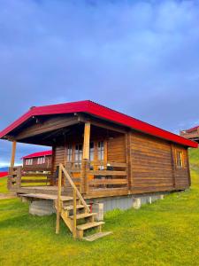 a wooden cabin with a red roof on a hill at Guesthouse Nypugardar in Höfn