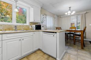 - une cuisine avec des placards blancs et une table à manger dans l'établissement Chalet chaleureux avec spa près de Mont-Tremblant, à Namur 11 autres photos