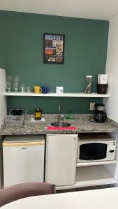 a kitchen with a counter with a sink and a microwave at Praia do Canto Apart Hotel quarto sala varanda - andar alto in Vitória