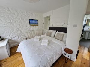 a white bedroom with a large bed and a wall at Primrose Cottage in Helston