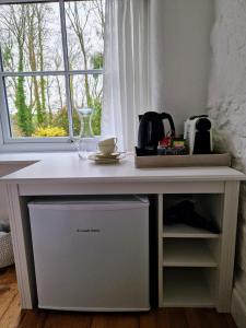 a white desk in a room with a window at Primrose Cottage in Helston