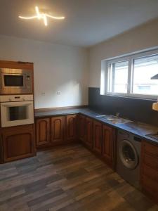 a kitchen with wooden cabinets and a washer and dryer at Chez Nino wifi gratuit in Beaulieu-sur-Loire