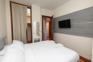 Cette chambre comprend un lit blanc et une télévision murale. dans l'établissement Apartment Forum IV, à Assago