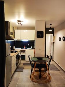 a kitchen with a table and a small kitchen with white cabinets at Cosy Studio à proximité de PARIS in Savigny-sur-Orge