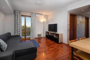 een woonkamer met een bank en een televisie bij Apartment Forum IV in Assago