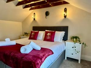 a bedroom with a bed with red and white pillows at Fallow Cottage, 3 Bedrooms - Stamford in Lincolnshire