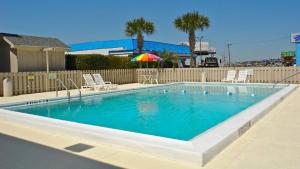 a swimming pool with chairs and an umbrella at Motel 6 - Pensacola West in Pensacola