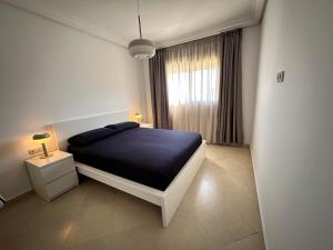 a white bedroom with a bed and a window at Riverside 2 in Tetouan