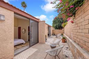 un patio con 2 sillas blancas y un dormitorio en Sundance Villas by Private Villa Management en Palm Springs