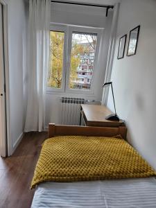 a bedroom with a bed and a desk and a window at Land Apartments in Zagreb