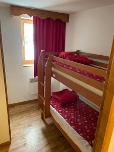 a bedroom with two bunk beds with red sheets at Appartement Chamrousse, 4 personnes - Village du Bachat in Chamrousse