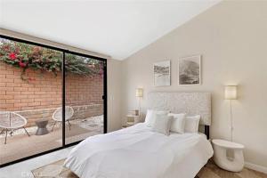 sypialnia z białym łóżkiem i ceglaną ścianą w obiekcie Sundance Villas by Private Villa Management w mieście Palm Springs