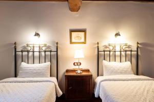 ナバコンセホにあるCasa Rural La Fuente del Jerteのベッドルーム1室(ベッド2台、ランプ付きテーブル付)