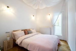 um quarto com uma cama com lençóis brancos e uma janela em Downtown Cozy Apartment Old Town em Bucareste