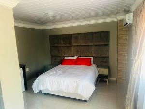 a bedroom with a bed with two red pillows at Sweet Nice Guest House in Ga-Rankuwa