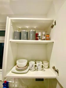 a shelf with cups and saucers in a kitchen at Lovely One bed apartment In London in London