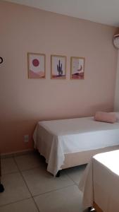 ジョアンペソアにあるApto em João Pessoa wifi e ar condicionadoのベッドルーム1室(ベッド2台付)が備わります。壁に3枚の写真が飾られています。