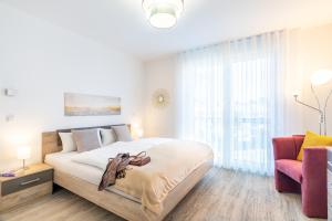 a white bedroom with a large bed and a chair at Apartment "Inselglück" - Haffresidenz in Garz
