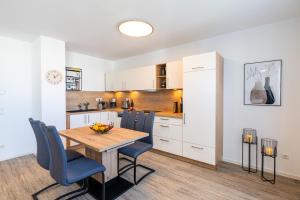 a kitchen with a wooden table and blue chairs at Apartment "Inselglück" - Haffresidenz in Garz