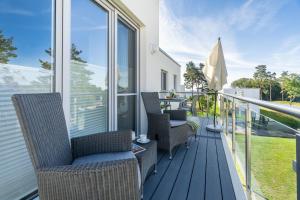 a balcony with chairs and an umbrella and a table at Apartment "Inselglück" - Haffresidenz in Garz