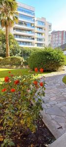 a garden with red flowers in front of a building at Full departamento, Metro Manquehue, Las Condes in Santiago