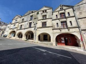 a large stone building with arches on a street at L'arcade de Fontenay in Fontenay-le-Comte