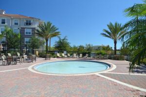 una piscina con mesas, sillas y palmeras en Vista Cay Getaway Luxury Condo by Universal Orlando Rental en Orlando