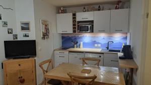 a kitchen with a table and a sink and a microwave at Appartement 2 chambres avec jardinet, piscine vue sur la montagne in Luz-Saint-Sauveur