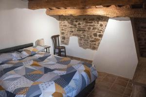 a bedroom with a bed and a stone wall at Mas el Cornut in Campdevánol