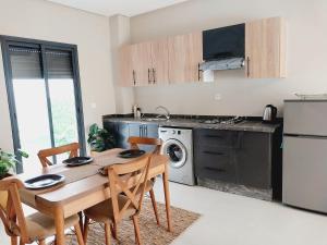 a kitchen with a wooden table and chairs in a kitchen at Airport mohamed 5 break apartments in Derroua
