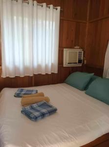 a bed with two towels on it with a window at Aundanao Oasis Beach in Samal