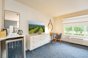 a room with a tv and a dresser and a window at The Inn at LBI National Golf & Resort in Little Egg Harbor Township