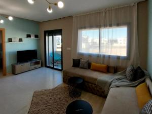 a living room with a couch and a large window at Airport mohamed 5 break apartments in Derroua