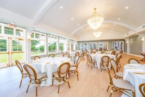un salón de banquetes con mesas y sillas blancas en The Inn at LBI National Golf & Resort, en Little Egg Harbor Township