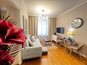 a living room with a white couch and a clock on the wall at Centrum Apartamenty Stare Miasto in Kraków
