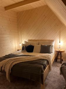 ein Schlafzimmer mit einem großen Bett und einer Holzwand in der Unterkunft Domki WIDOKÓWKA in Bukowina Tatrzańska