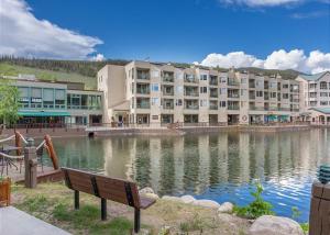 a park bench in front of a large building with a lake at Keystone Lakeside Condo in Keystone