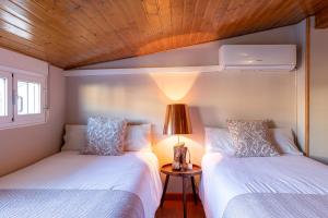 2 camas en una habitación pequeña con lámpara en APARTAMENTO TURÍSTICO ABUELO TEÓFILO, en Tornavacas