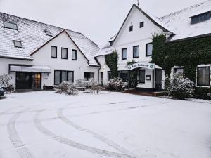 uma entrada coberta de neve em frente a dois edifícios em Hotel Rademacher em Wittmund