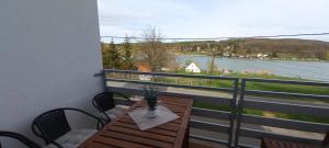 een balkon met een tafel en stoelen en uitzicht op het water bij Onix-Vital Apartman Orfű in Orfű