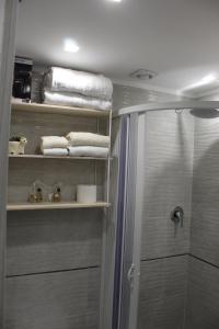 a bathroom with a shower and towels on shelves at La Piccola Mole - Turin Cozy Apartment in Turin +27 photos