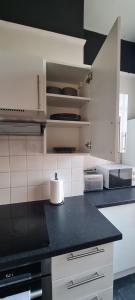 a kitchen with white cabinets and a black counter top at Lovely One Bed Apartment in St Leonards in St. Leonards