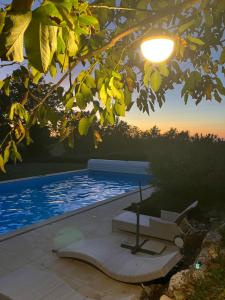 a pool with a chair and a table and a lamp at Le clos mirélie in Gaujac