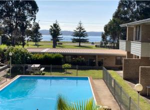 a swimming pool in a yard next to a house at 2 bedroom beach apartment in Batehaven