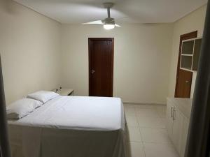 a bedroom with a white bed and a brown door at Brisa Bicanga in Serra